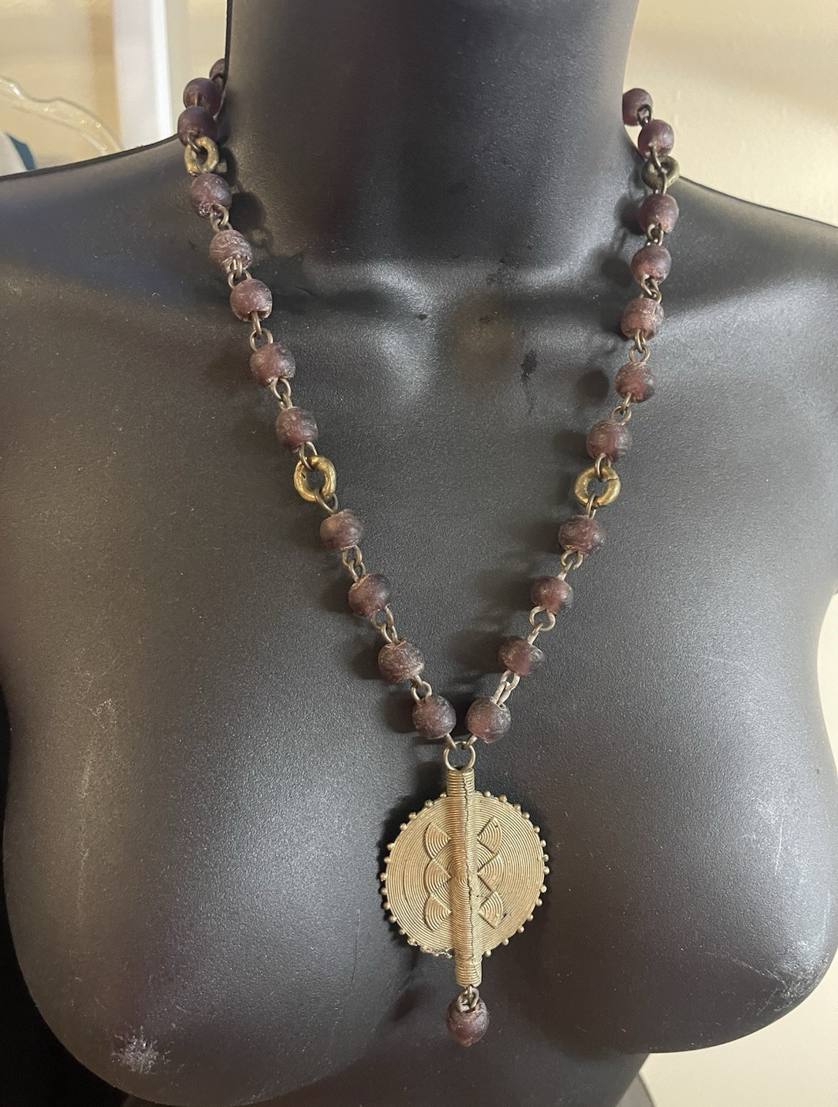 Handcrafted African necklace features dark, textured bicone beads.