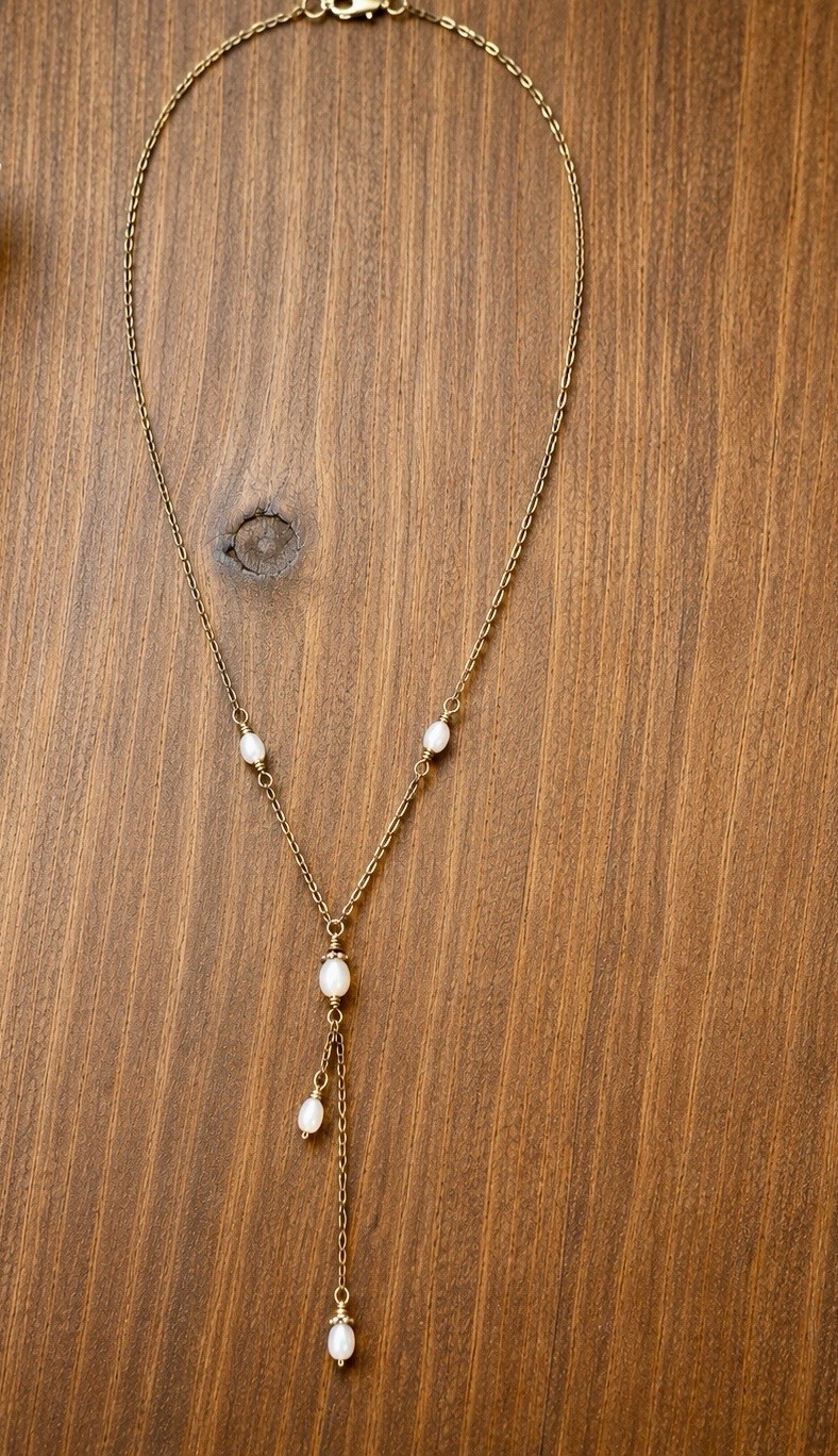 Delicate gold-tone lariat necklace with soft pearl-like bead accents