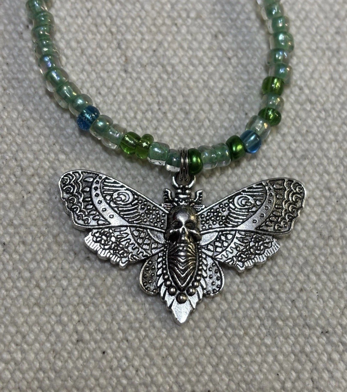 Metal Moth pendant on glass Beaded stretch necklace.