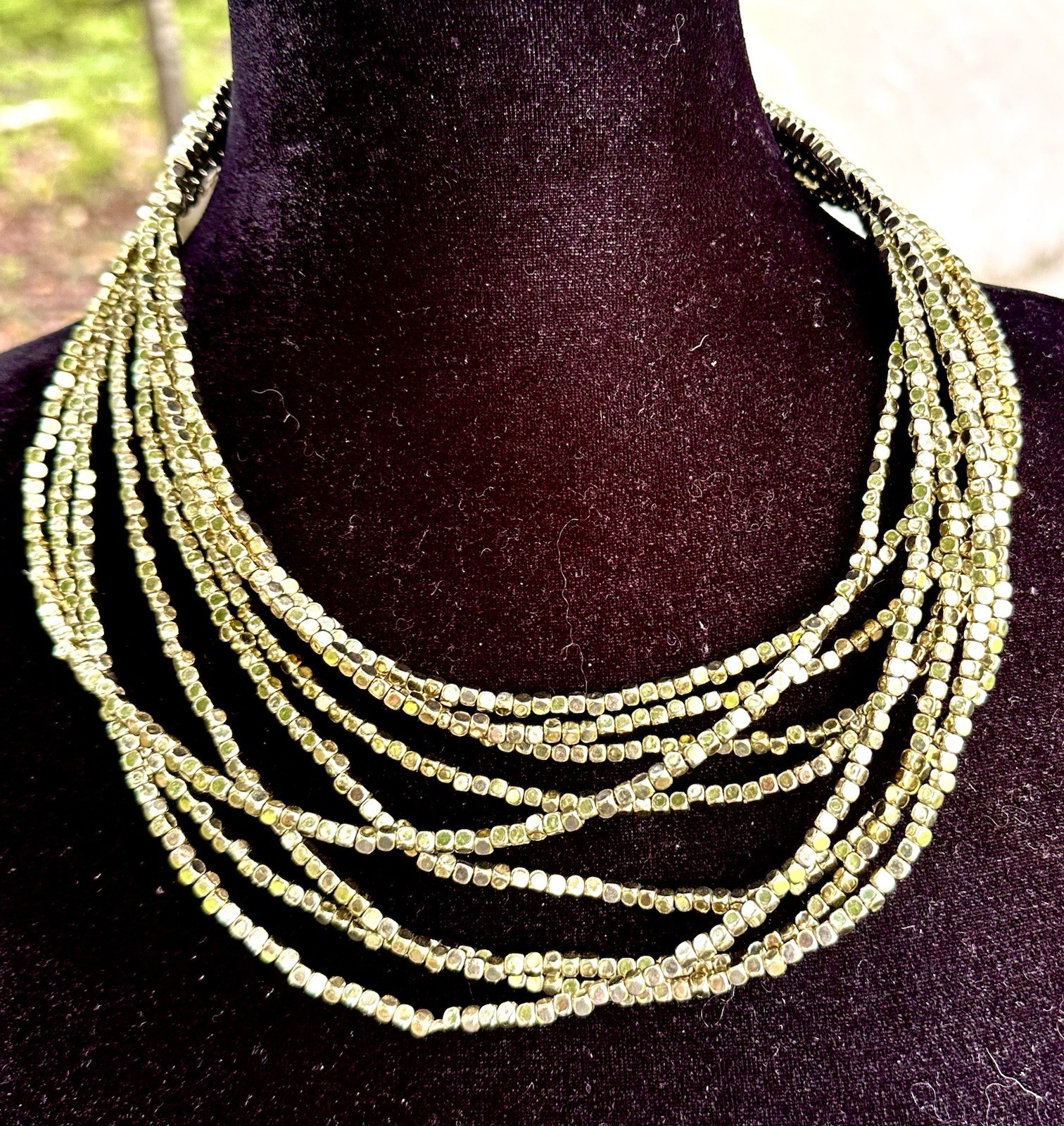 multi-strand bib necklace appears to be crafted from metallic-plated hematite