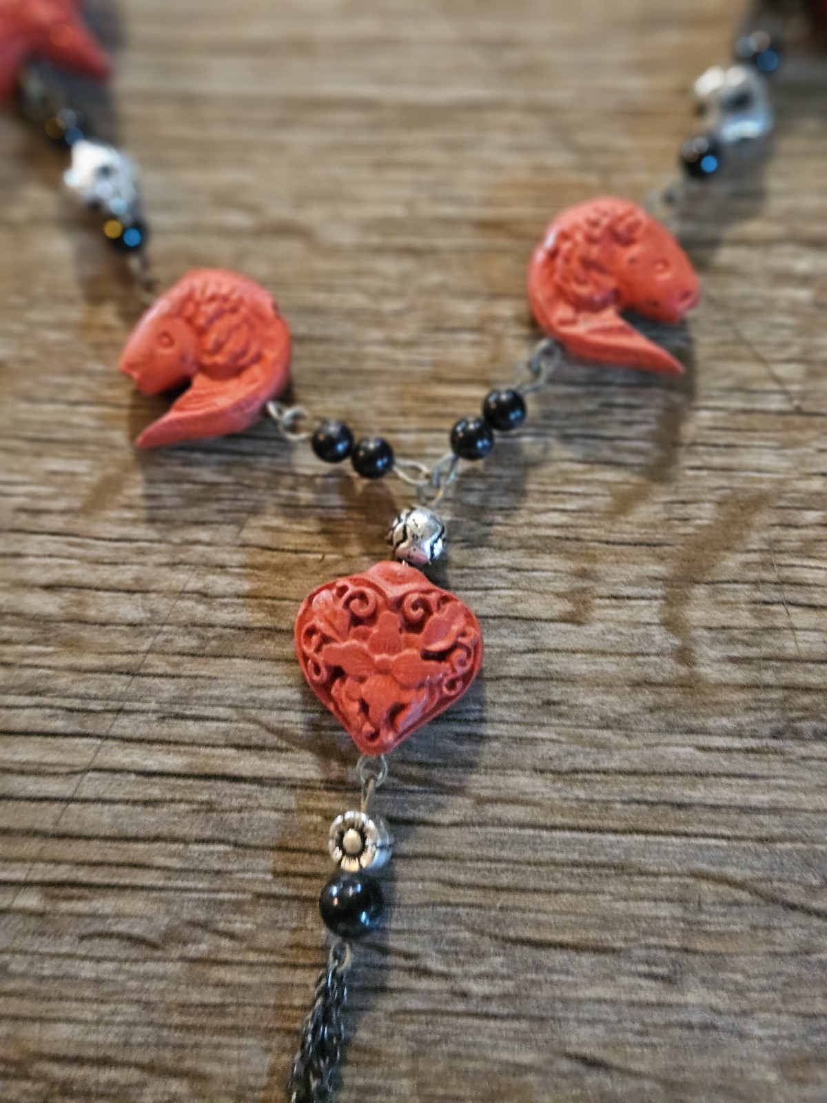 This red l and black lariat necklace features carved starfish and shrimp charms