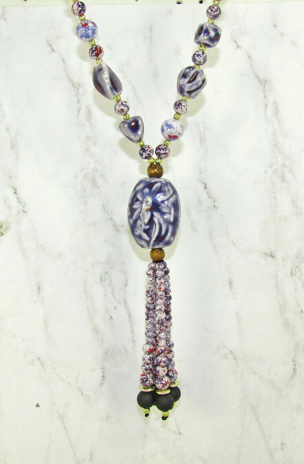 Purple ceramic beaded tassel necklace with wood beads attached to a leather cord