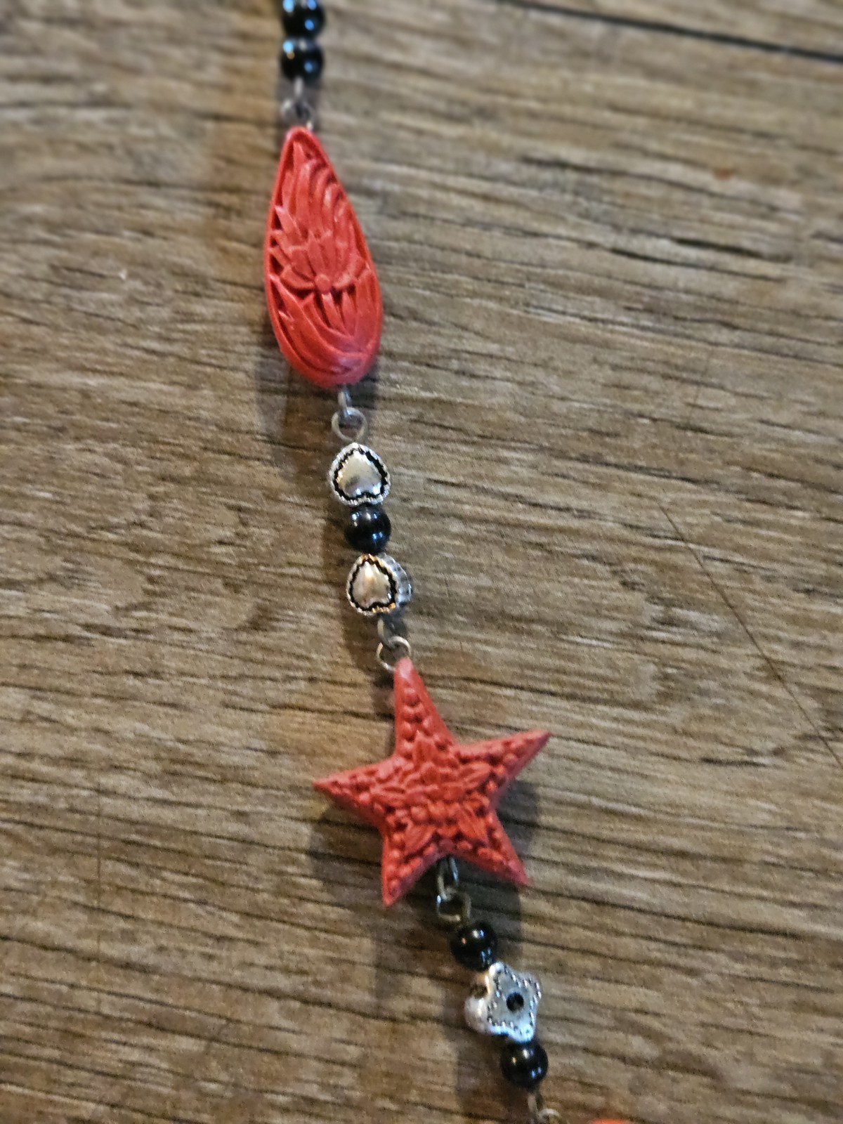 This red l and black lariat necklace features carved starfish and shrimp charms