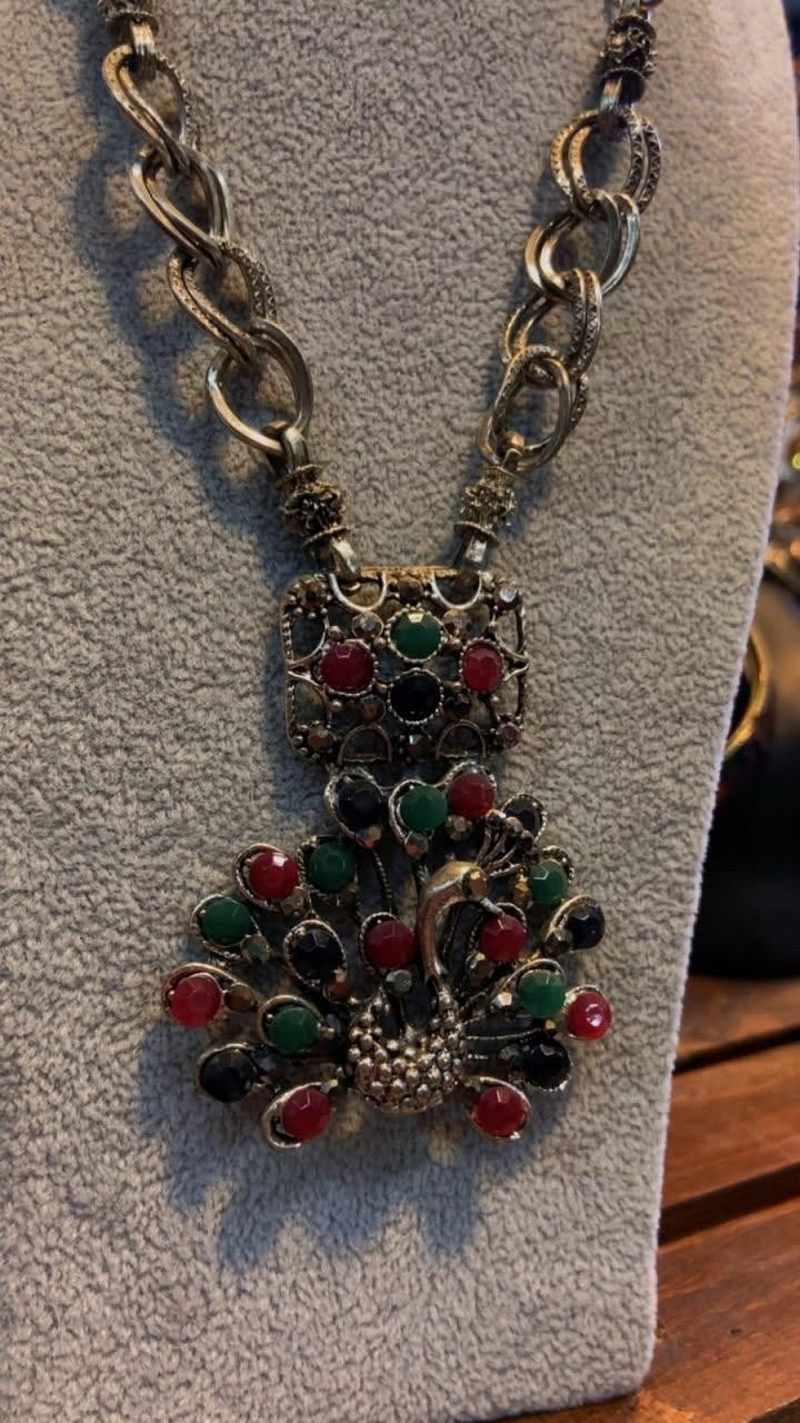 Vintage Peacock Necklace With Red, Green, And Black Stones On An Ornate Pendant.