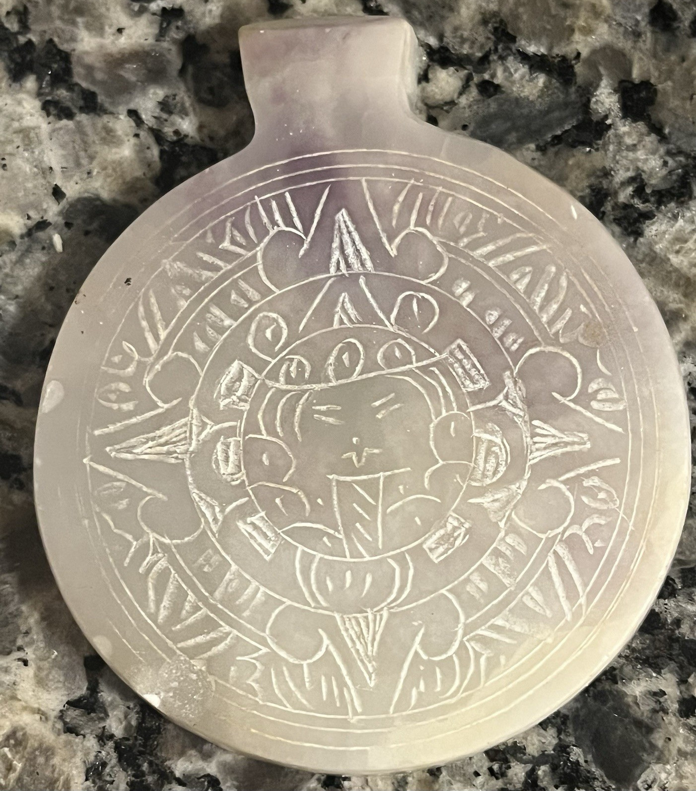 This a vintage Mexican Aztec sun medallion pendant, likely made of carved white