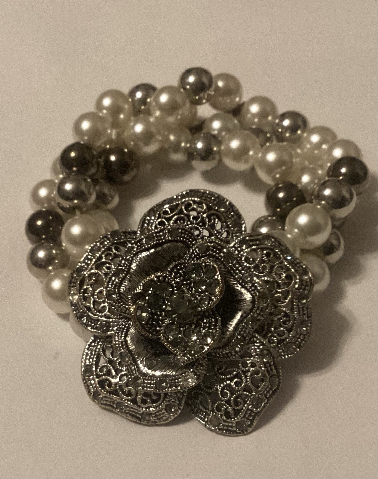Three Strand Stretch Bracelet Featuring Faux Pearls With Large Flower Center