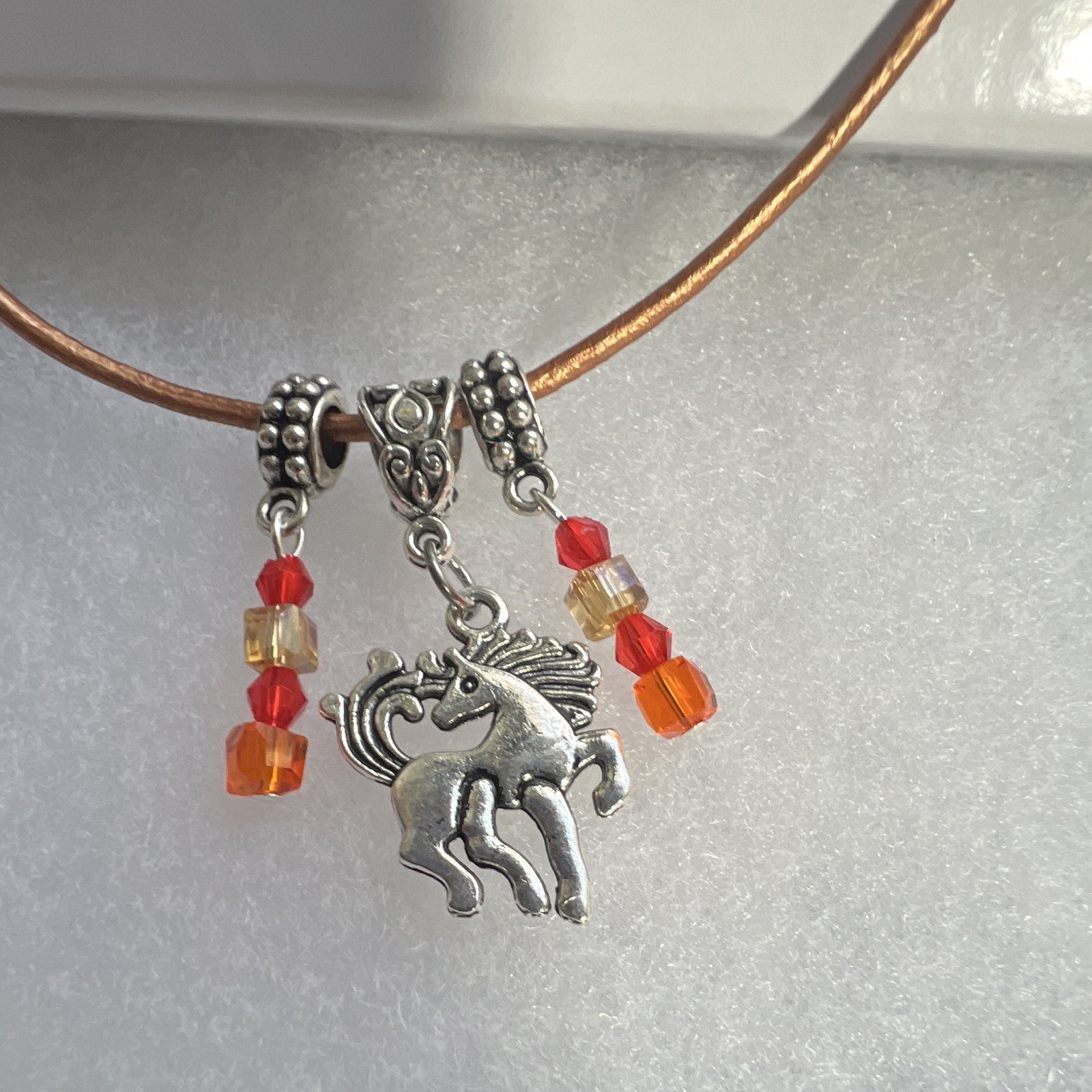 Prancing horse, orange crystals, bronze, leather cord, silver components,