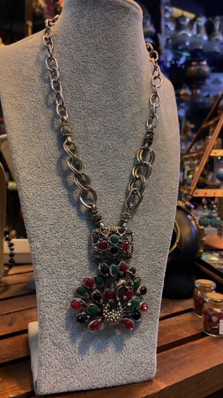 Vintage Peacock Necklace With Red, Green, And Black Stones On An Ornate Pendant.
