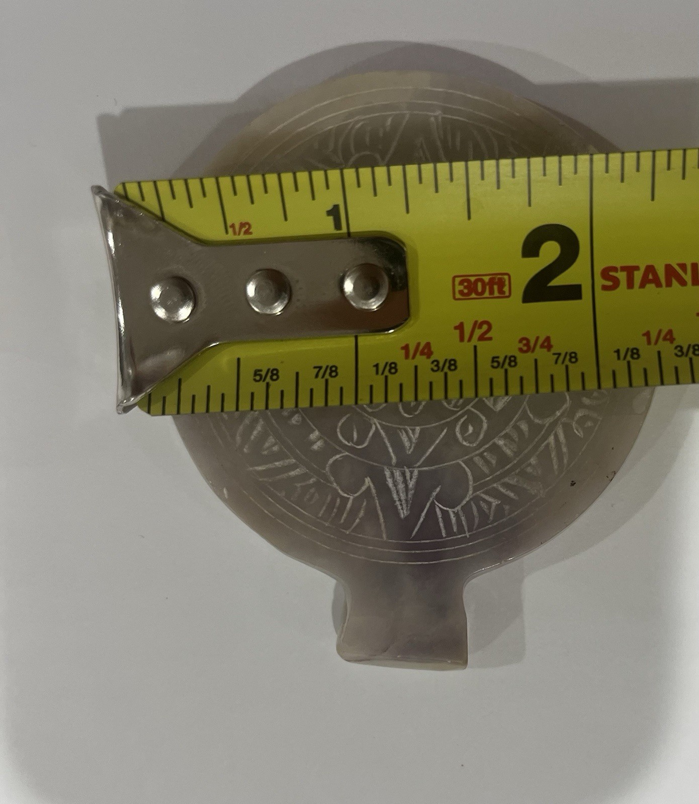 This a vintage Mexican Aztec sun medallion pendant, likely made of carved white