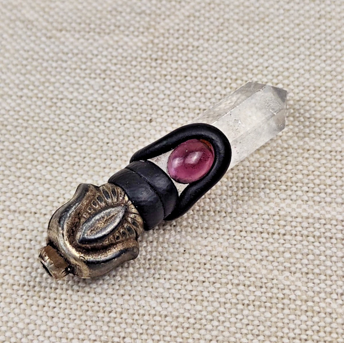 A pendant or talisman made of rock crystal and accented with a rose-red stone