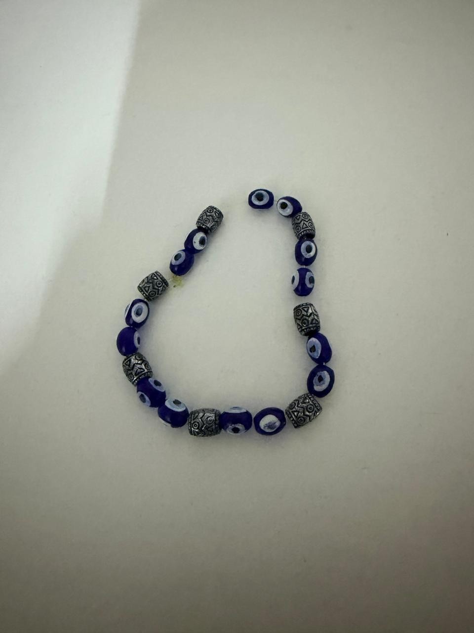 Blue Evil Eye Beaded Bracelet With Silver Accents On White Surface Clean Style.